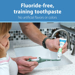 Lifestyle image of an adult squeezing Dr. Brown's fluoride-free toothpaste onto a green child's toothbrush at a sink