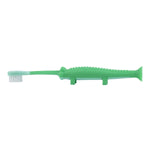 Side profile of a green crocodile-shaped toddler toothbrush showing bristles, textured back and suction-cup base on a white background.