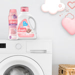 Dreft Blissfuls bottle displayed next to a Dreft detergent jug on top of a washing machine, playful cloud and heart graphics