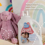 Dreft Family detergent bottle placed on bedding next to a pink plush bunny and rainbow pillow with text about cozy fabric
