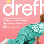 Close-up of Dreft packaging text and crawling toddler wearing teal overalls on pink background