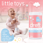 Smiling baby playing with toys beside a Dreft All Purpose Wipes tub and copy 'little toys' on a pink background