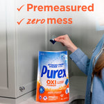 Person dropping a blue detergent pac into an open Purex Oxi Power product pouch with 'Premeasured zero mess' text