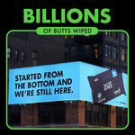 Outdoor billboard-style ad reading 'BILLIONS OF BUTTS WIPED' with a DUDE Wipes package pictured on a city building corner.