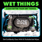 Close-up of a DUDE Wipes XL pack sitting in snow with visible DUDE WIPES logo and product callouts on the black package.