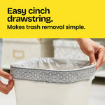 Close-up of hands cinching a patterned drawstring bag around a rectangular trash can with 'Easy cinch drawstring' headline.