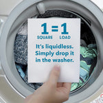 Hand holding a detergent sheet card in front of a washer door reading “1=1 Square = Load. It’s liquidless. Simply drop it in the washer.”