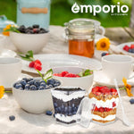 Outdoor table setting with Emporio logo, two clear dessert cups filled with parfaits placed among bowls and jars