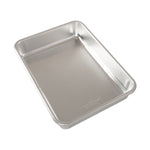 Empty aluminum rectangular baking pan photographed at an angle on a white background showing smooth interior and rounded corners