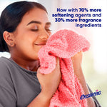Person smelling a pink towel alongside Ensueño logo and copy about increased softening agents and fragrance
