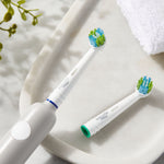 Lifestyle photo of two Equate replacement brush heads on a bathroom tray, one attached to an electric toothbrush handle.