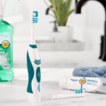 Equate electric toothbrush upright on a bathroom counter with replacement head and toothpaste tube nearby in a lifestyle scene.