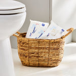 Bathroom scene with a wicker basket holding multiple Equate flushable wipes packs beside a toilet