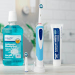 Equate electric toothbrush standing on a charging base with extra brush head, mouthwash bottle and toothpaste blurred in bathroom background.