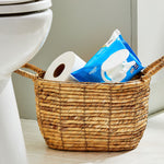 Equate flushable wipes pack placed in a woven bathroom basket next to a toilet paper roll in a bathroom setting