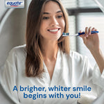 Smiling woman holding a blue-and-white Equate toothbrush near her teeth with the equate logo visible in the corner.