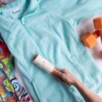 Hand rolling an Evercare lint roller over a light blue zippered jacket to remove lint and debris