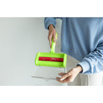 Person holding green Evercare pet hair remover with clear tray opened to show collected hair on red roller
