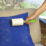 Hand holding Evercare lint roller removing pet hair from a blue cushion on beige sofa