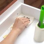 Hand wiping crumbs with a lint-roller sheet inside a drawer while an Evercare roller rests nearby