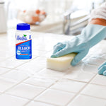 Evolve bleach tablet bottle placed on a tiled surface beside a gloved hand scrubbing tiles with a sponge.