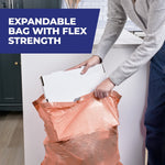 Person placing a cardboard box into an expandable peach-colored trash bag demonstrating flex strength and capacity