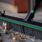 Tight detail of broom bristles and handle socket sweeping dried leaves on concrete