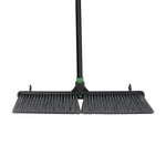 Front-facing close-up of push broom head showing dense flagged bristles and central handle socket