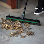 Lifestyle shot of broom sweeping dried leaves from concrete floor with shoe visible in background