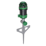 Close-up angled shot of green and black pulsating lawn sprinkler on a pointed metal stake