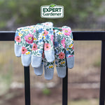 Floral gardening gloves draped over a black metal rail with blurred outdoor background and Expert Gardener logo