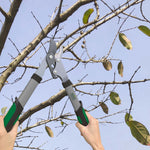 Two hands holding Expert Gardener loppers cutting a branch in a tree with sky in the background.