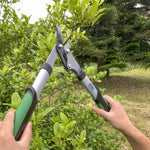 Person using Expert Gardener loppers to trim a leafy shrub, lopper blades open and handles gripped.