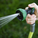 Lifestyle shot of the green and black spray nozzle being used, water streaming from the head