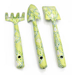 Three lime-green patterned hand tools (rake, trowel, small shovel) arranged vertically on white background