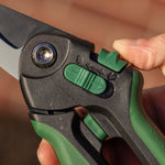 Close-up of a finger operating the green safety lock on an Expert Gardener bypass pruner, showing blade pivot and latch.