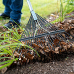 Rake tines raking dried leaves at ground level, focus on the head and metal tines gathering debris