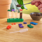 Close-up lifestyle shot of test tubes, colored reagent capsules and a spoonful of soil over a test rack