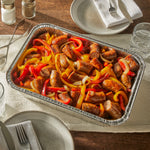EZ Foil aluminum roaster pan shown on a table set with plates, filled with cooked sausage, peppers and onions