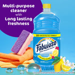 Fabuloso blue cleaner bottle staged with cleaning sponge, cloths and lemon on a bright background
