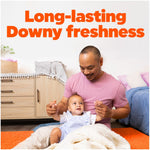 Smiling man playing with a baby in a home scene under large copy reading 'Long-lasting Downy freshness'
