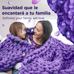 Lifestyle image of a smiling woman and child wrapped in a chunky purple blanket with floral graphic accents
