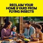 Family eating at an outdoor table in a backyard setting beneath a large yellow banner that reads 'RECLAIM YOUR HOME & YARD FROM FLYING INSECTS'.