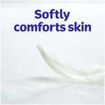 Soft-focus close-up of a white feather on a pale surface with large text reading 'Softly comforts skin'
