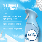 Close-up Febreze Air Mist bottle head against a blue sky background with product benefit text and hanging linens.