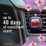 Febreze Auto vent clip attached to a car air vent with pink refill and cherry blossom petals, plus text claiming up to 40 days of consistent scent.