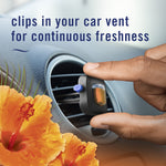 Hand installing a Febreze AUTO vent-clip into a car vent with tropical hibiscus illustration and promotional copy