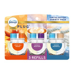 Febreze Luxe Plug refill variety pack showing three clear refill bottles labeled Crisp Fall Breeze, Cuddle Weather, Serene Snowfall on holiday-themed backing.