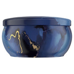 Side-profile close-up of the navy marbled Febreze Ocean candle tin with decorative gold accents and fitted lid.