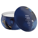 Studio image of a Febreze Ocean candle tin with lid leaning against the bowl, showing label text and three unlit wicks.